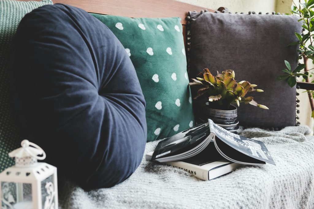 Two books beside three assorted color pillows